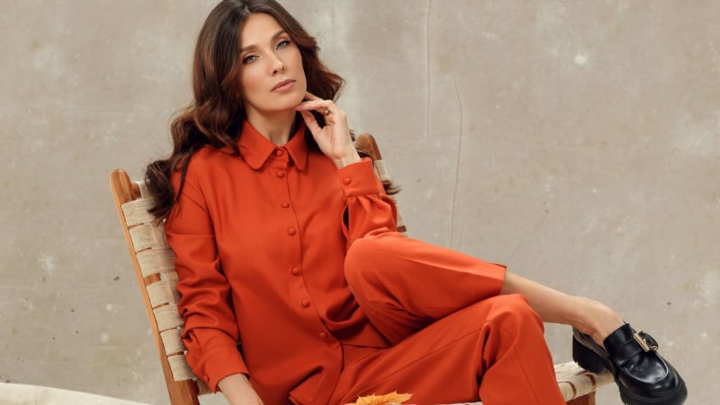 Stylish Woman in Orange Suit Sitting on a Chair